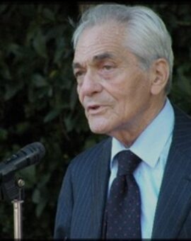 Professor Jacques-Louis Binet at a speaking engagement in front of a leafy background